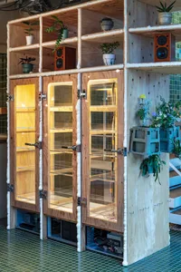 An industrial style interior design featuring wooden cabinets and shelves with plants and speakers.