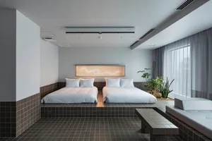 Modern minimalist bedroom with two beds, tiled flooring, and soft fabrics.