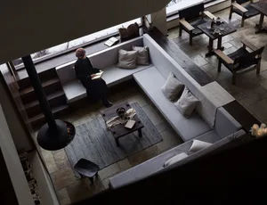 A minimalist living room showcasing a cozy corner with a fireplace, neutral-colored sofa, and low wooden coffee table.