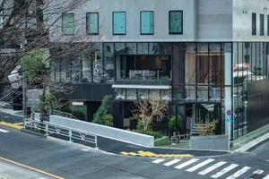 Modern city coffee shop facade with glass front and greenery.