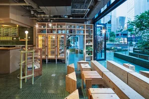 Modern wooden coffee shop interior with open shelving and large windows.