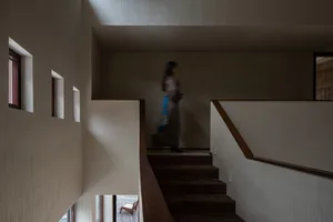 A modern interior design featuring a wooden staircase with a woman walking down it.