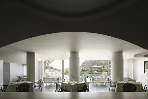 A sleek, modern restaurant interior with white stone flooring, white walls, and a minimalist design.