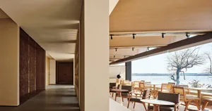 A modern restaurant with wooden furniture and a view of the lake.
