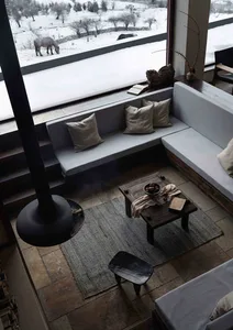 A modern living room with a wood and concrete floor, a sectional sofa, and a hanging fireplace.