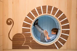 A child reads a book in a circular wooden alcove with a蜗牛图案和白色条纹。