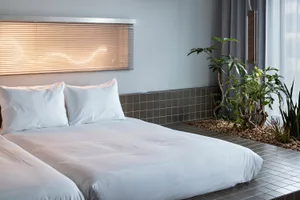 A minimalist bedroom with a bed and tile flooring.