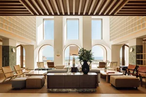 A modern hotel lobby featuring natural light through large windows and contemporary furniture.