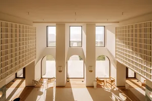 Modern interior design featuring exposed concrete walls, large windows, and warm lighting.