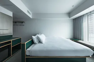 Minimalist bedroom featuring a white bed and clean lines.