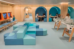 A modern playroom featuring blue soft furniture and interactive gaming areas.