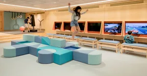 A modern playroom with colorful, modular soft furniture and electronic games.