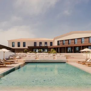 A modern residential space featuring a poolside lounge area with concrete and wooden elements.