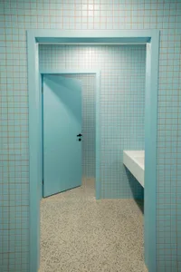 Modern public restroom with blue-tiled walls and open door.