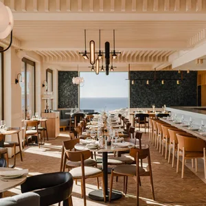 Modern restaurant interior featuring natural wood accents and an ocean view.