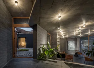 Modern, industrial-style living space featuring concrete walls, exposed beams, and minimalist furniture.