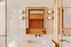 A minimalist bathroom with white tiles and wooden accents