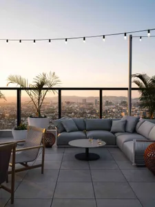 Outdoor rooftop lounge area with modern furniture, concrete floor, and hanging lights.