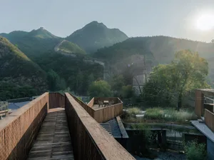 Modern wooden bridge over mountain with stone walls and metal railings