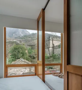 Modern bedroom with wood accents and view of mountains through large windows.