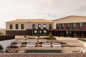 A modern building with sandstone terraces and a pool.