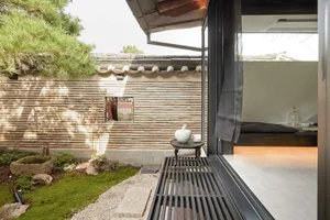 A view of a modern minimalist residential exterior with stone walls and wooden elements.