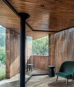 A modern living space with wooden flooring, glass walls, and a green armchair.