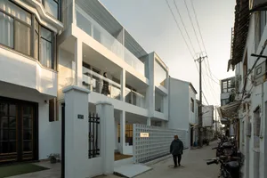 Modern residential building with white walls, glass windows, and metal railings and doors.