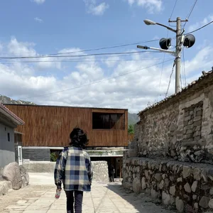A person walking on a street with a wooden building in the background.