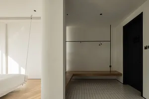 A minimalist bedroom featuring a floating bed, white walls, and a wooden floating bench.