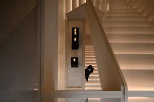 A modern staircase with light-colored marble steps and walls, illuminated by warm lighting.
