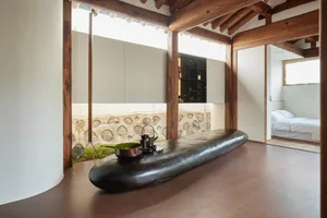 Industrial-style residential interior featuring a wooden table and stone wall
