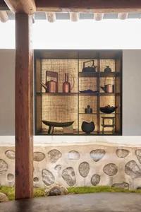 A traditional interior design featuring wooden shelves adorned with various decorative items, including teapots, bottles, bow