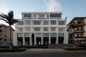 Modern concrete building with large windows and white facade.