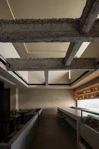 Industrial-style restaurant bar with concrete beams and brick accents.