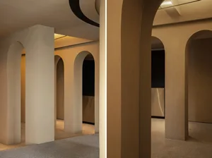 A modern interior space featuring concrete columns and a corridor with arches.