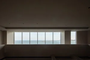 A modern living room featuring a large glass window overlooking the ocean.