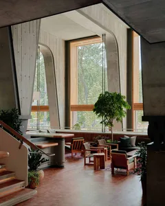Industrial-style lobby featuring concrete walls, large windows, and wooden furniture.