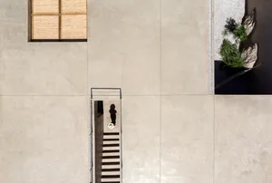 A minimalist staircase constructed from concrete, viewed from above with a person standing at the bottom.