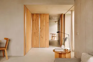 Minimalist room with wooden walls, light-colored floor, and a small table with a lamp and vase.