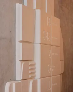 A wall of beige concrete cubes with numbers and labels indicating different levels and areas of a building.