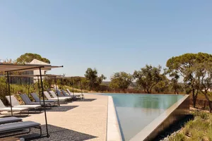 Modern holiday resort with concrete poolside and lounge chairs.