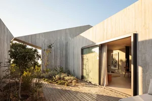 Modern, minimalist residence with a concrete exterior and large glass windows.