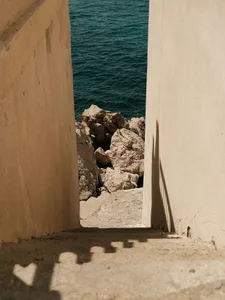 A concrete pathway leading to water, framed by tall walls.