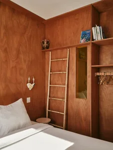 Modern minimalist bedroom with wooden walls and built-in storage solutions.