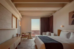 A minimalist bedroom featuring wooden furniture and textile accents.