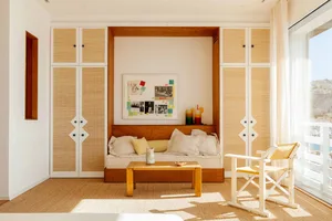 A minimalist bedroom with a woven texture, featuring a built-in bed with soft furnishings, a wooden coffee table, and a white