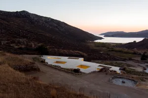 Modern architectural structure with concrete material on a hillside overlooking water.
