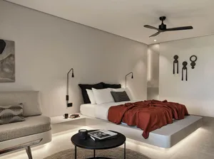 A modern bedroom featuring a concrete bed platform with built-in lighting, minimalist furnishings, and a ceiling fan.