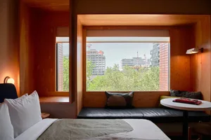 A modern bedroom with a bed, window seat, and wooden walls and furnishings.